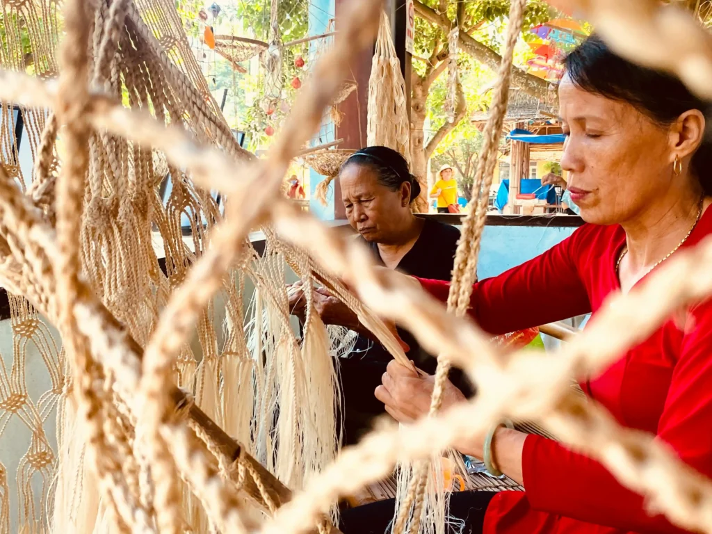 Artesanas tejiendo hamacas de cuerda a mano en un taller tradicional al aire libre.