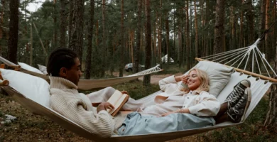 Pareja descansando juntos en una hamaca en medio de un bosque, disfrutando de un momento de lectura y relajación.