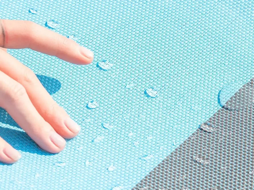 Tela textil azul impermeable de hamaca portátil con gotas de agua y mano tocando la superficie.